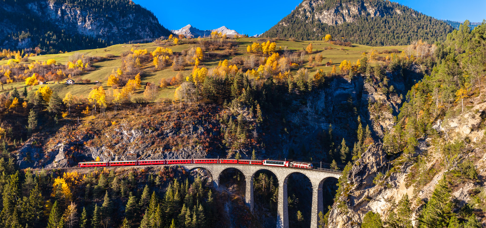 Zug fährt über eine Brücke in den Bergen