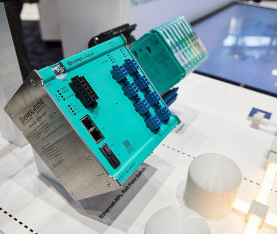 Der Ethernet-APL Rail Field Switch von Pepperl+Fuchs, im Hintergrund weitere FieldConnex-Komponenten auf einem Messeexponat.